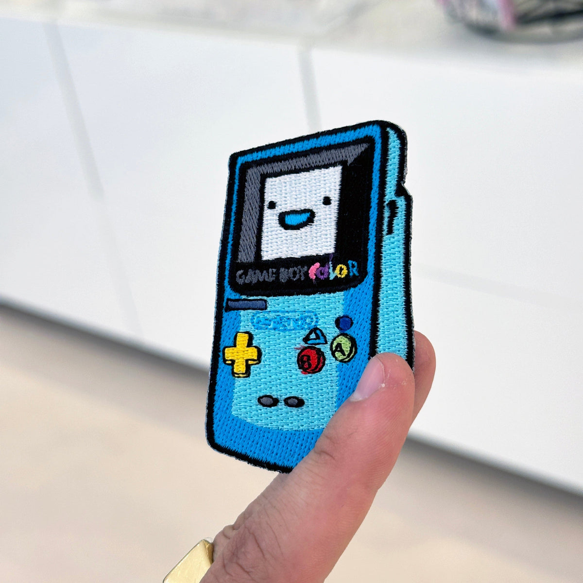 Display of GBC x BMO embroidered patch showing textured stitching – crossover anime patch – Akira Gallery
