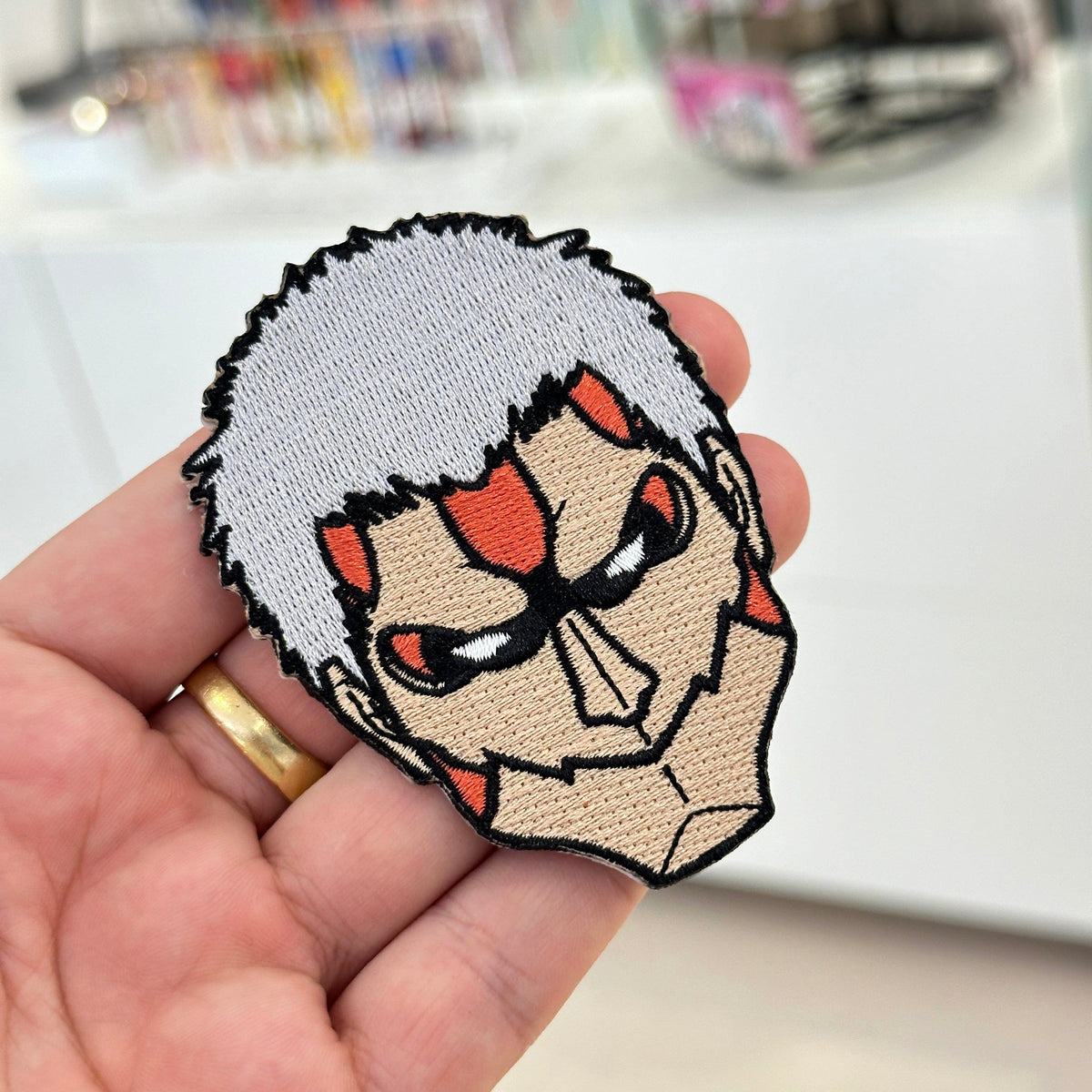 Display of Armored Titan embroidered patch showing textured stitching – anime patch – Akira Gallery
