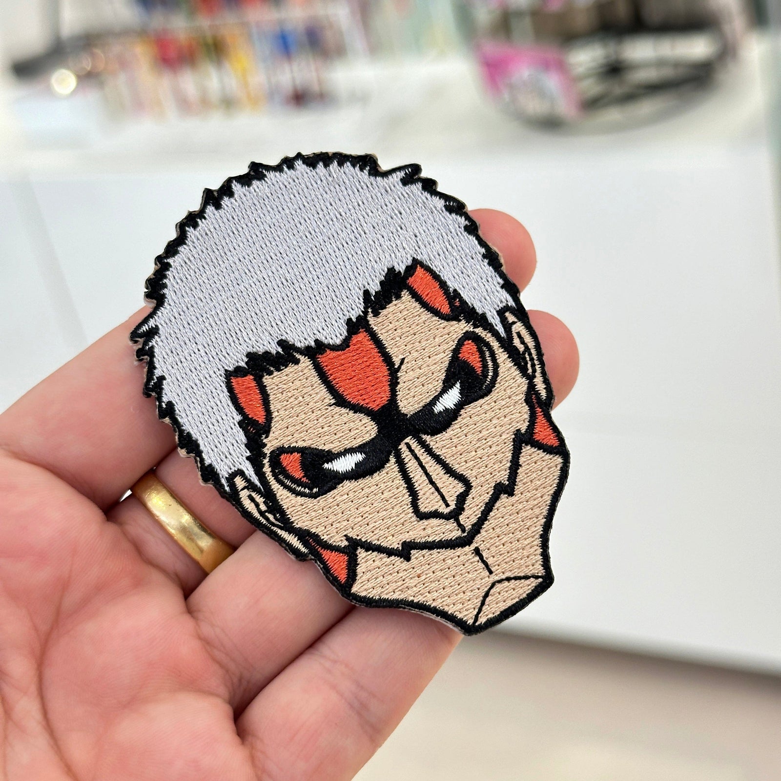 Display of Armored Titan embroidered patch showing textured stitching – anime patch – Akira Gallery

