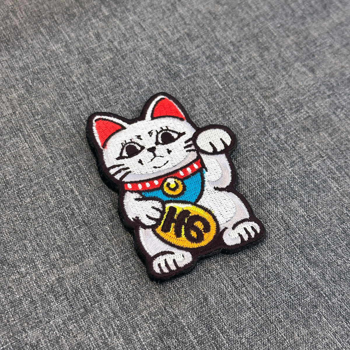 Display of Turbo Granny Maneki Neko embroidered anime patch inspired by Dandadan with velcro backing – Akira Gallery
