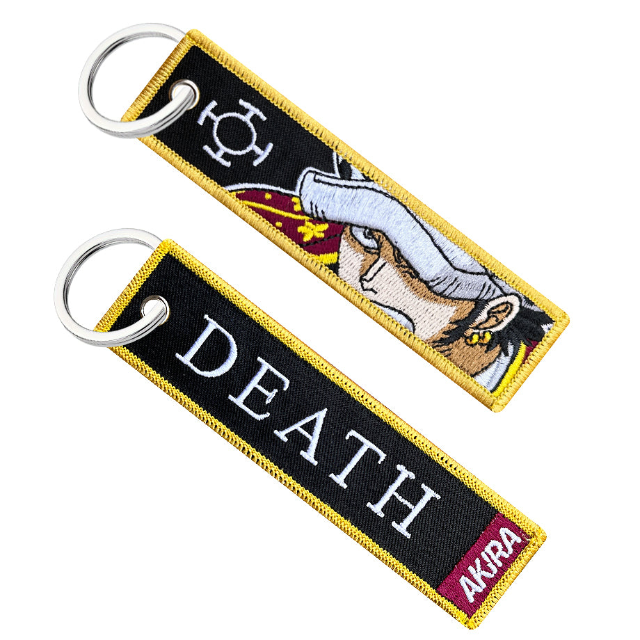 Double-sided embroidered keychain of Trafalgar Law from One Piece. One side features the word "DEATH" with a red "AKIRA" label, and the other side shows Law's face with his signature hat and the Heart Pirates' Jolly Roger.