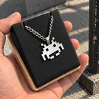 Space Invaders Stainless Steel Necklace featuring the iconic Martian displayed on a black block