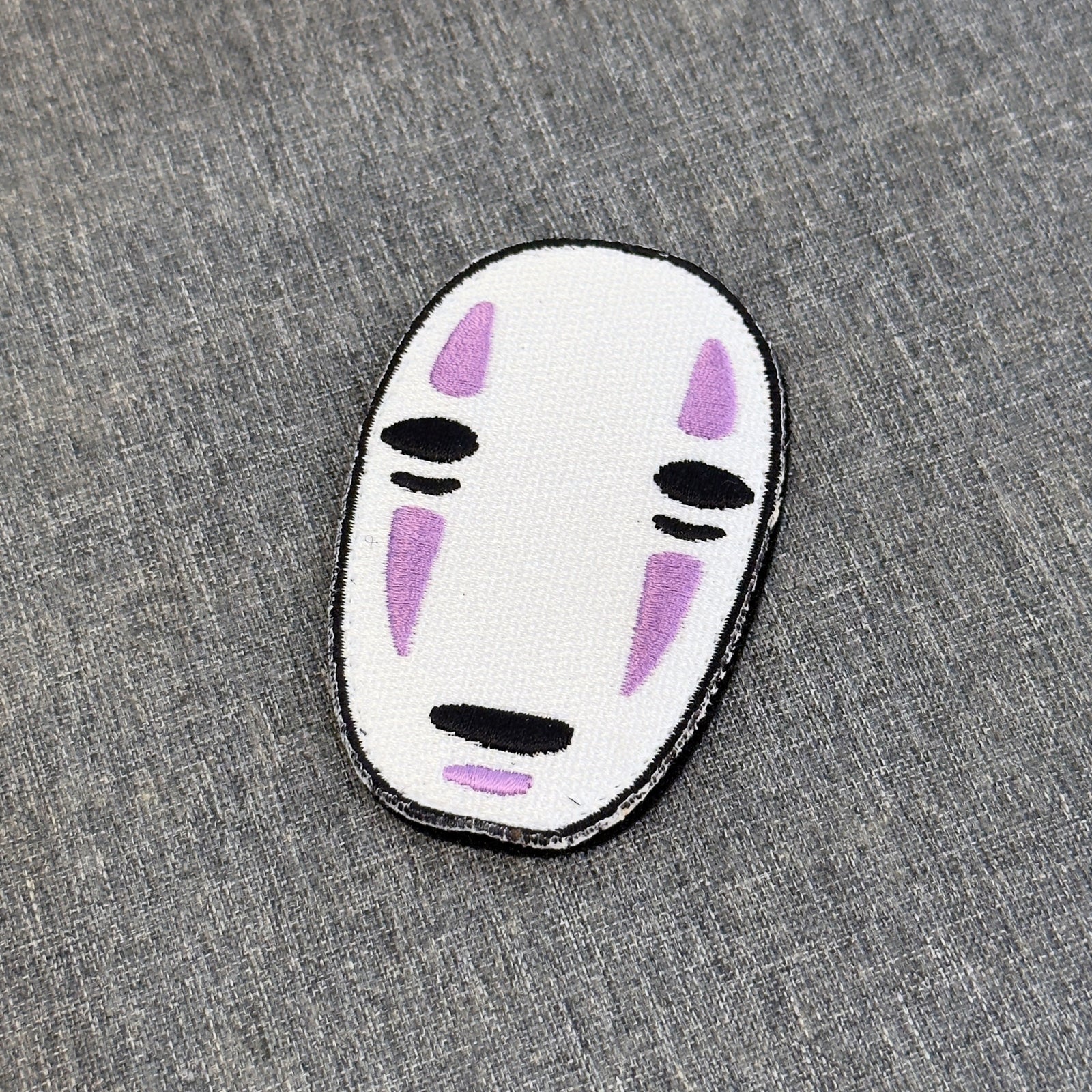 Display of Kaonashi embroidered anime patch inspired by Spirited Away with velcro backing – Akira Gallery
