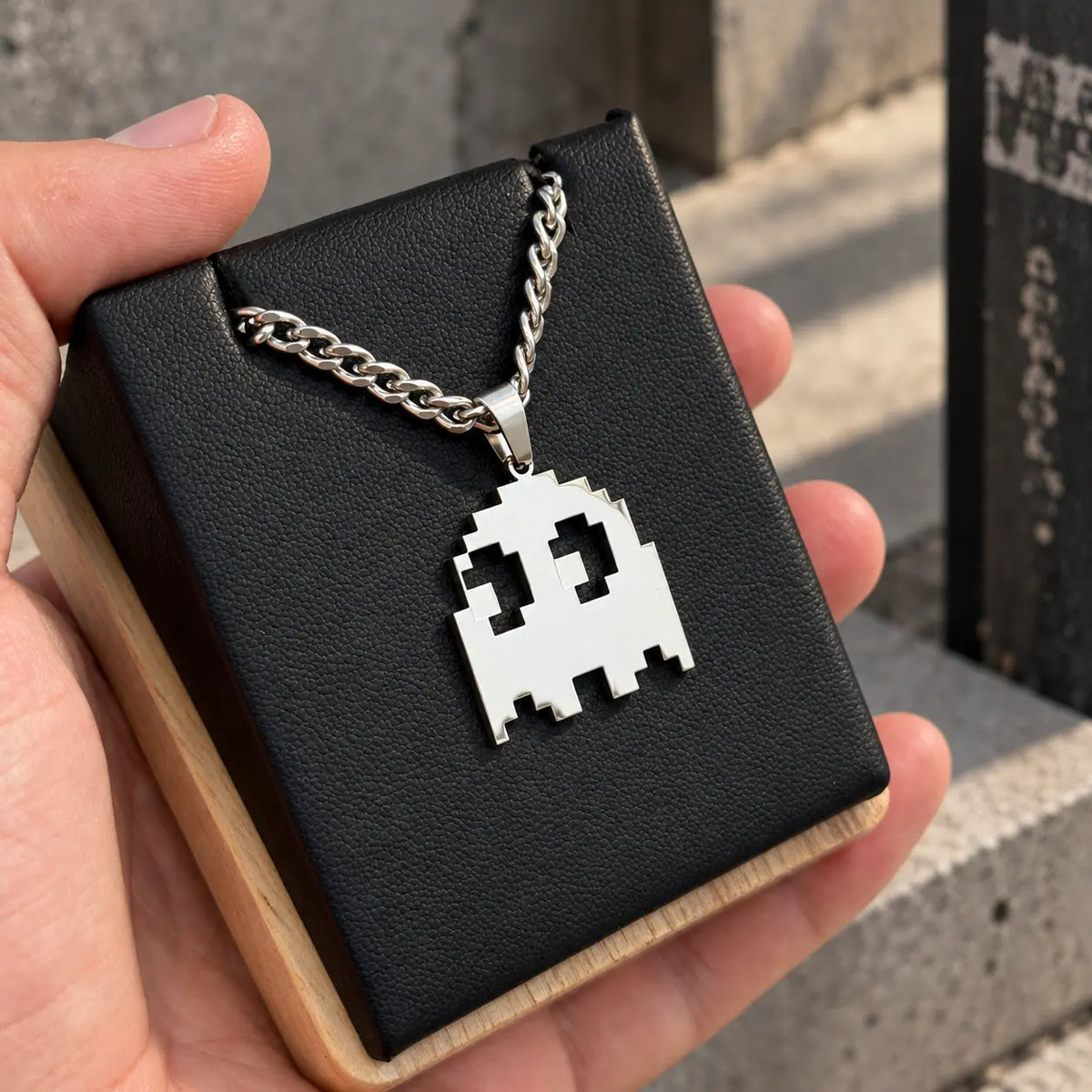 Pacman Stainless Steel Necklace featuring the iconic ghost of the arcade game displayed on a black block