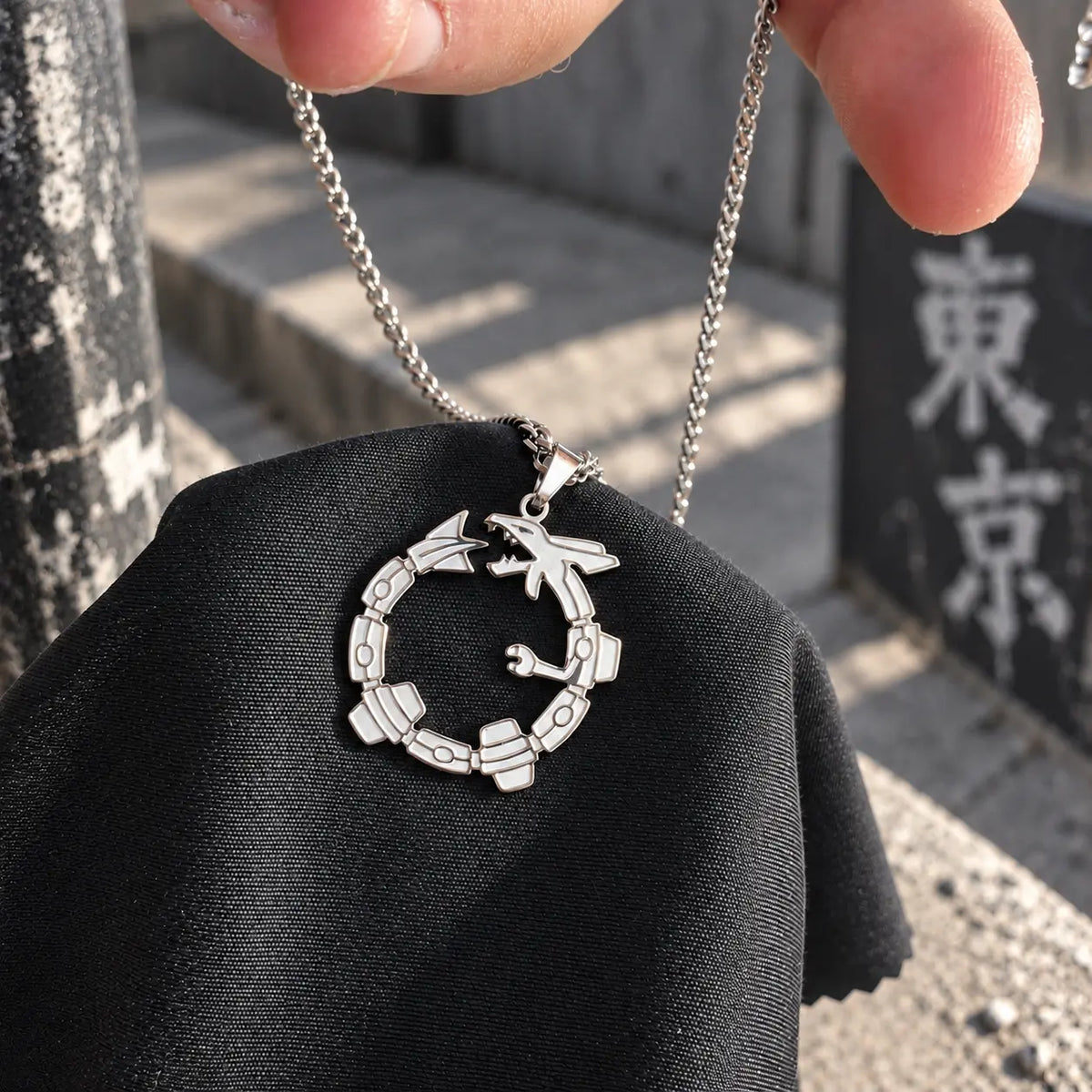 Rayquaza Stainless Steel Necklace engraved with 50 cm Chain from anime Pokemon Held by a hand over a cloth