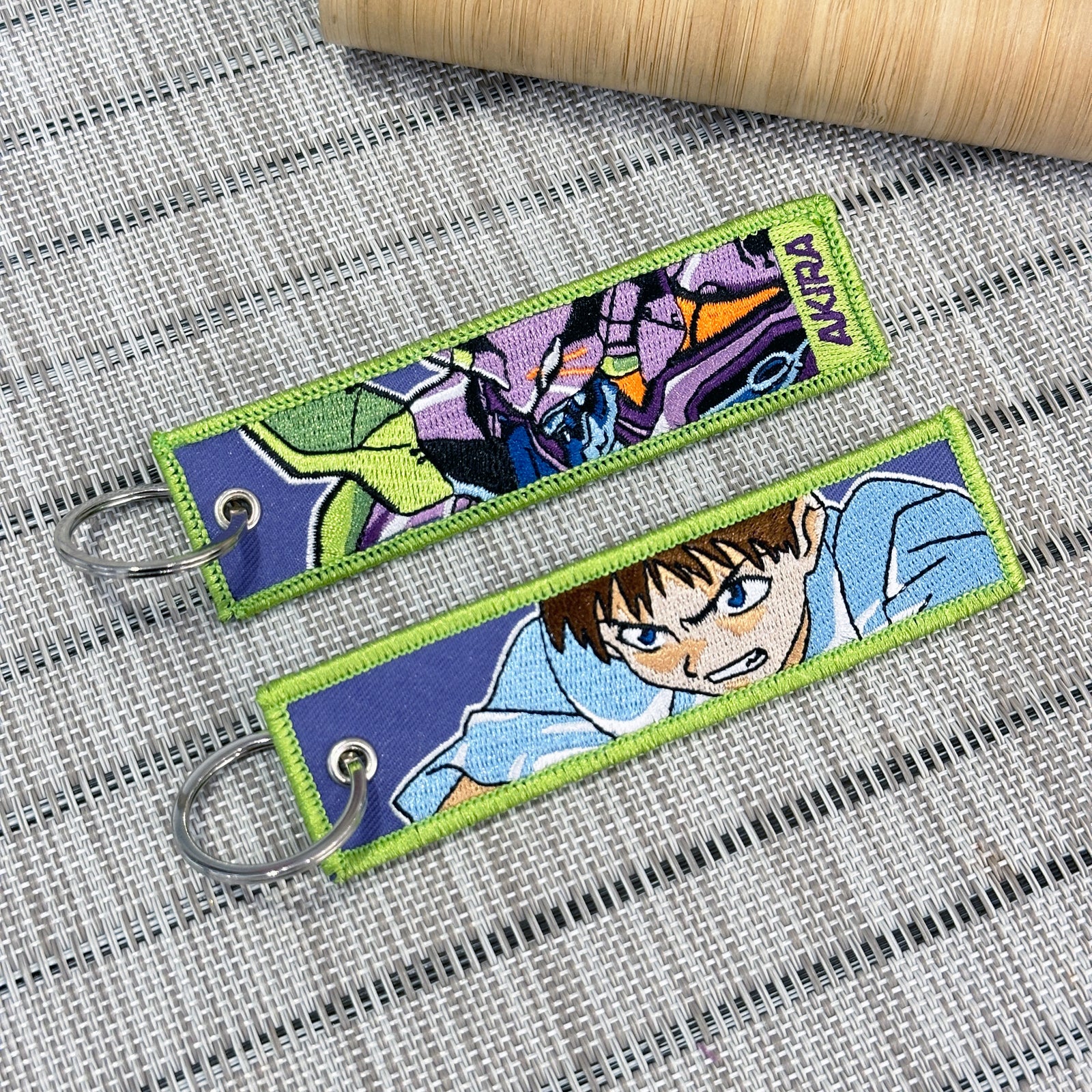 Double-sided embroidered keychain of Shinji from Evangelion. One side features the mecha Eva 01, and the other side shows Shinji with an angry expression