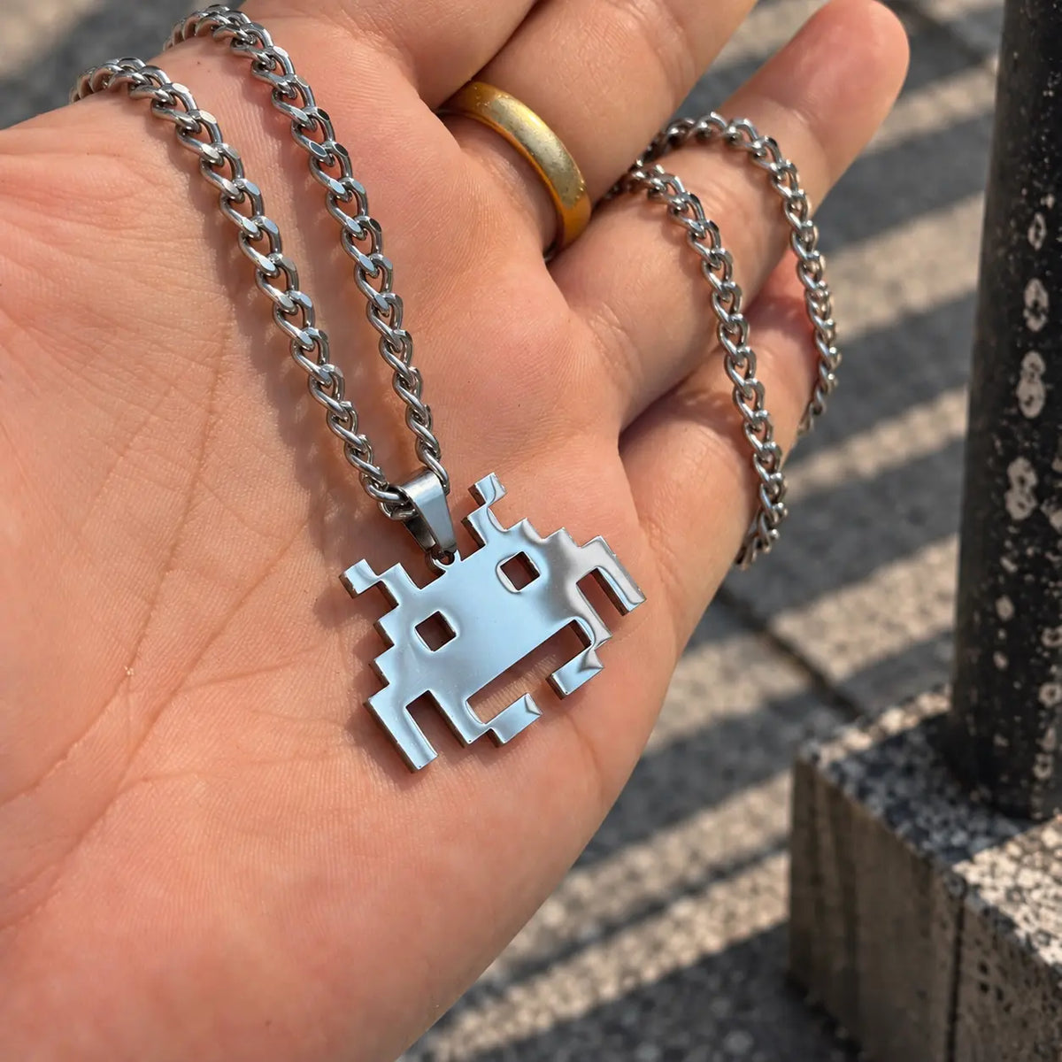 Space Invaders Stainless Steel Necklace featuring the iconic Martian held by hand