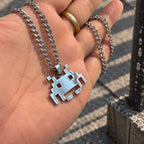 Space Invaders Stainless Steel Necklace featuring the iconic Martian held by hand