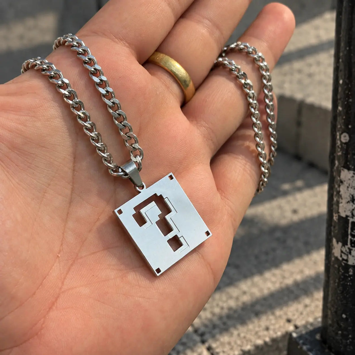 Super Mario Stainless Steel Necklace featuring the question block held by hand