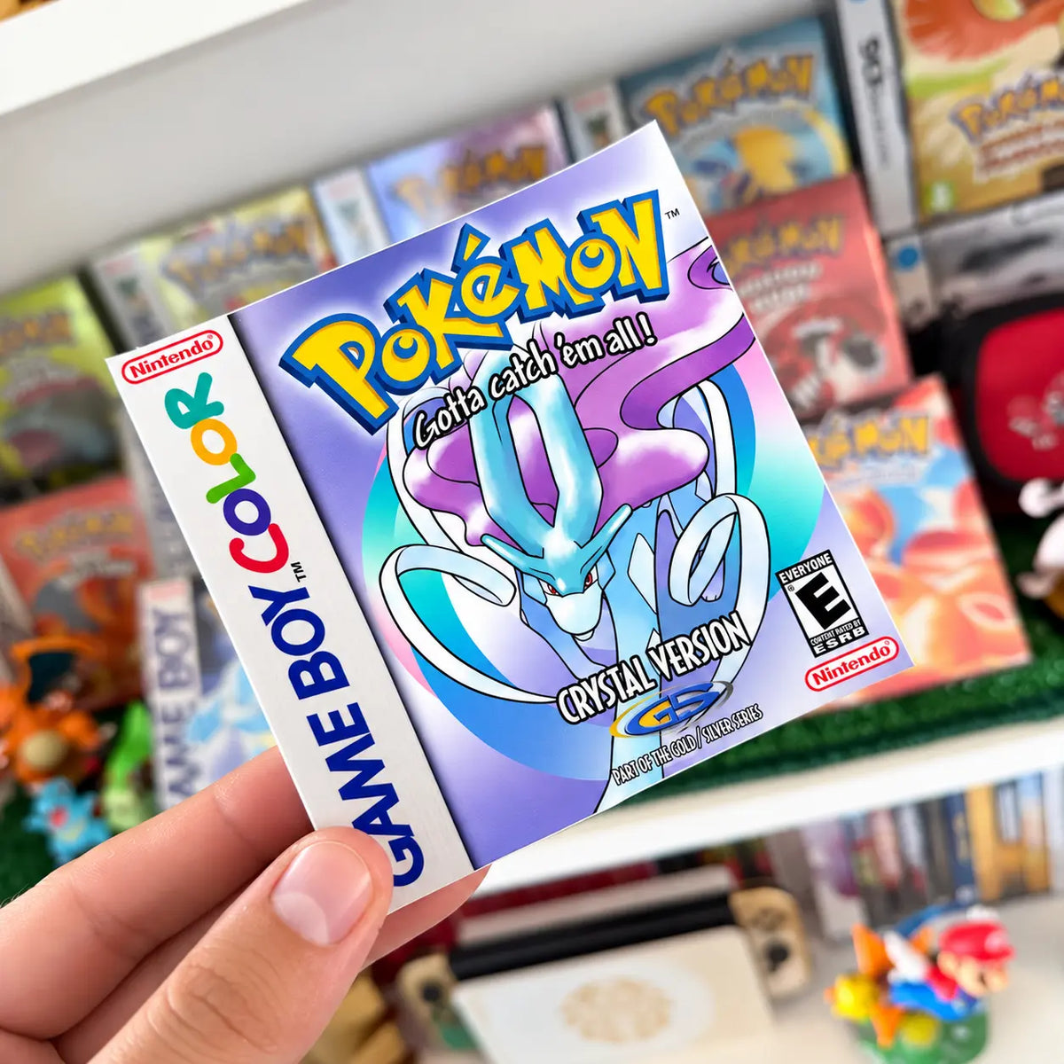 Pokémon Crystal Version sticker with Suicune held in front of a retro Pokémon game collection