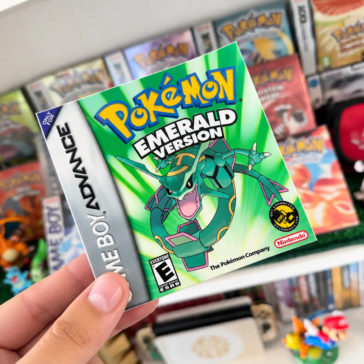 Pokémon Emerald Version sticker with Rayquaza held in front of a retro Pokémon game collection