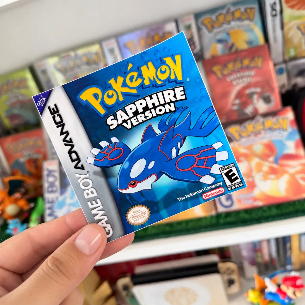 Pokémon Sapphire Version sticker with Kyogre held in front of a retro Pokémon game collection